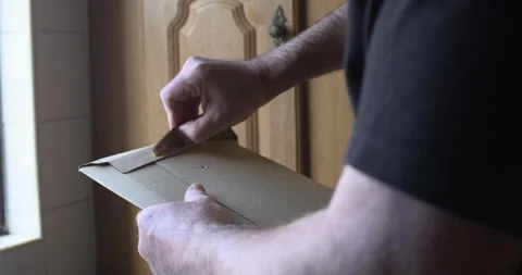 Man opening unboxing cardboard envelope parcel adhesive seal Vídeos de archivo 341510535