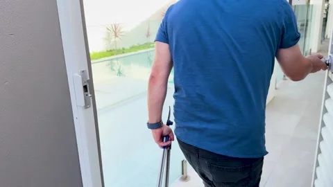 Man opening white louvre gate and walking into swimming pool area at luxury.. Vidéo 333489899