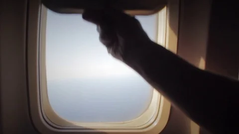 Man opens an airplane window and looks out during air travel. Happy. Man Stock Footage 82774241