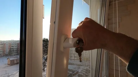 A man opens and closes a window on a balcony with his hand during the day. Stock Footage 304689290