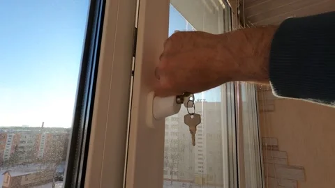A man opens and closes a window on a balcony with his hand during the day. Stock Footage 304689294
