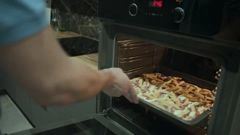 Man opens and puts pizza in the oven to cook, tracking camera Stock Footage 155647762