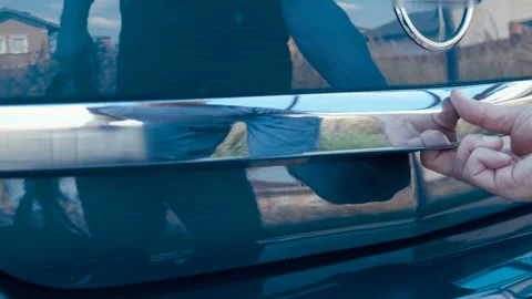 The man opens the back door of the blue car, puts the black bag in there Stock Footage 138255006