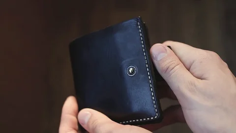 A man opens a black leather wallet in which only one dollar Stockbeeldmateriaal 129612828