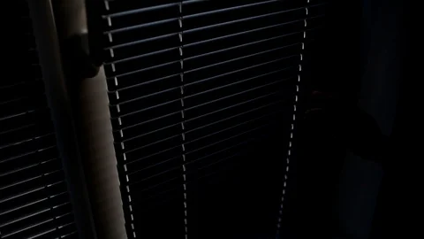 A man opens the blinds, and a cyclist rides on the street. Stock Footage 127801676
