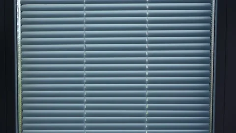 A man opens the blinds on a window in his room Stock Footage 135828724