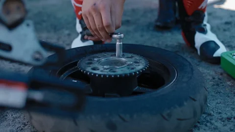 A man opens the bolts on a motorcycle wheel Stock Footage 128972849