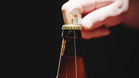 A man opens a bottle of beer on a black background. Slow motion video Stock Footage 171488279