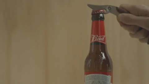 A man opens a bottle of beer "BUD" with an opener Stock Footage 142703446