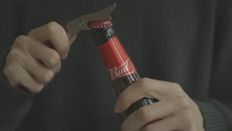 A man opens a bottle of beer "BUD" with an opener. Closeup Stock Footage 142703453