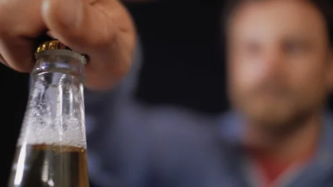 Man opens a bottle of lager beer.Male hand unscrews the cap on a bottle of beer Stock Footage 106356196
