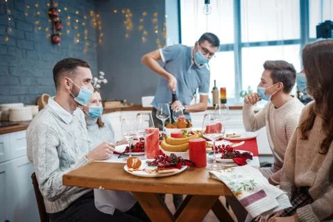 A man opens a bottle of red wine in the company of friends. All have protective Stock Photos