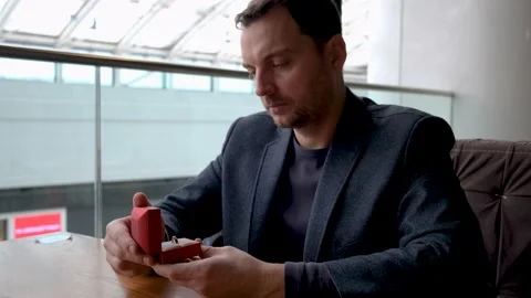 A man opens a box with a wedding ring, looks at it thoughtfully and sadly and Stock-Footage 169473892