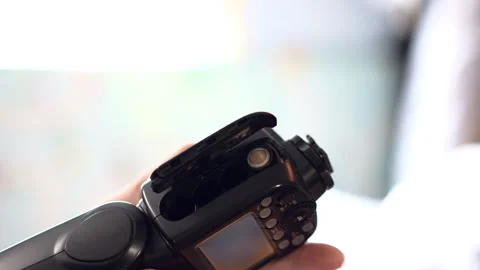 A man opens a camera flash compartment and carefully inserts batteries Video stock 329104016