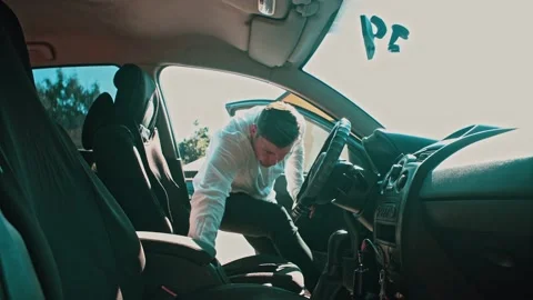 The man opens the car door and sits down in the driver's seat. Stock Footage 150153396