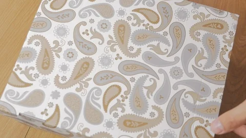 The man opens a cardboard box with different ties and pours them on the wooden Stock Footage 92636880