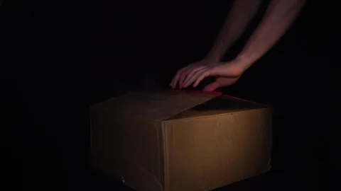 A man opens a cardboard box from which smoke comes and a multi-colored light Stock Footage 129960221
