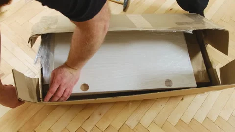 Man opens cardboard box with white plywood boards on parquet floor Stock Footage 304400266