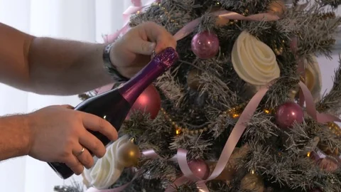 A man opens champagne against the backdrop of a Christmas tree 스톡 동영상 81821923