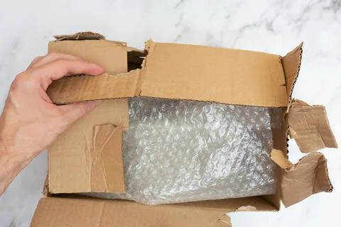 Man opens a damaged and torn cardboard box to transport things. Top view. Bubble Stock Photos
