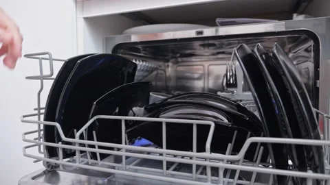 Man opens dishwasher and pulls out clean black crockery set Stock Footage 213339825