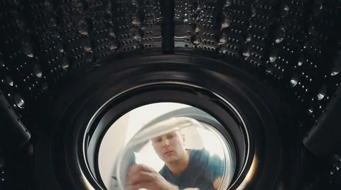 A man opens the door and load the laundry into the washing machine 動画素材 64253960