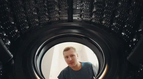 A man opens the door and load the laundry into the washing machine 動画素材 64254091