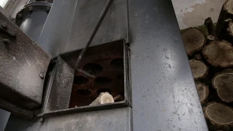 The man opens the door and throws firewood in boiler. Lit the fire. Stock Footage 73484547