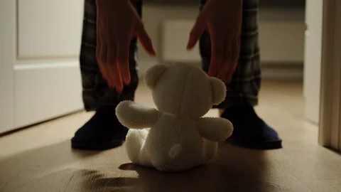 Man Opens The Door In The Dark Room And Picks Small Plush Bear Toy Up Video stock 124623634