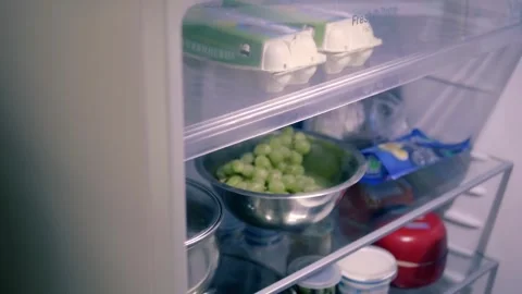 Man opens the door of a modern refrigerator and gets the necessary products Stock Footage 297787709
