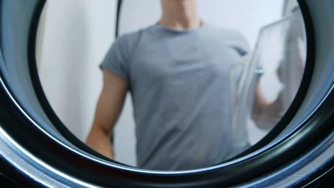 A man opens the door of the washing machine and load the clothes into it - View Stock Footage 114892025