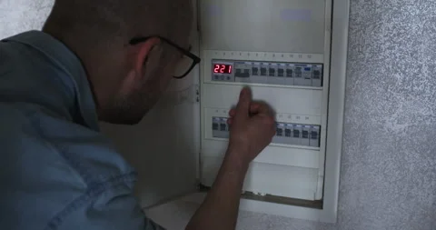 Man opens electrical circuit breaker panel switching on fuse Stock Footage 302026707