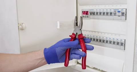 Man opens electrical distribution box with pliers in hand Stockbeeldmateriaal 302027854