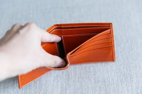 Man opens an empty orange leather wallet. Foto stock