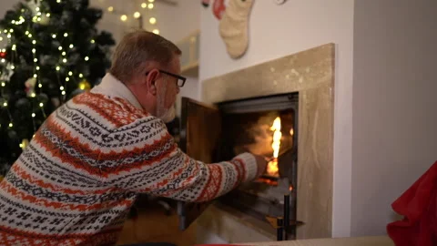 The man opens the fireplace and spreads the red-hot charcoal, adds firewood to Stock Footage 143400667