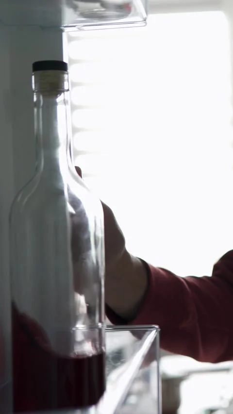 Man opens fridge and grabs alcohol bottle in quiet kitchen. Stock Footage 317687669