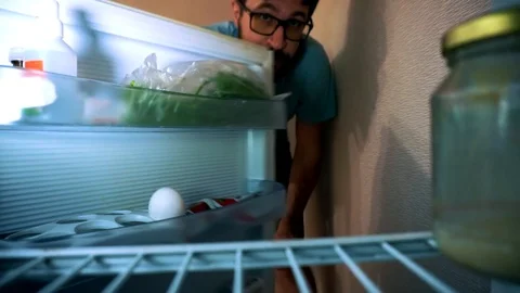 The man opens the fridge, he is half empty, shows his face and takes the jar. 스톡 동영상 102896264