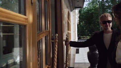 Man opens front door and lets woman through. Couple walks into a building. Vídeo Stock 160572621