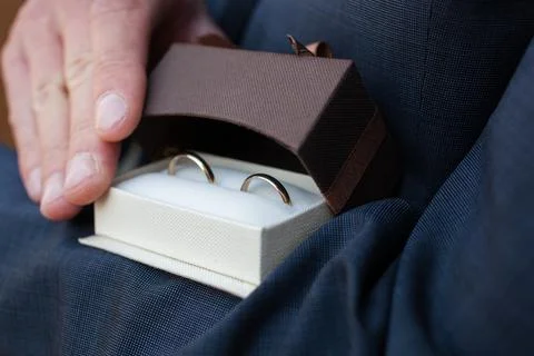A man opens a gift box with wedding rings, showing them to the frame Stock Photos