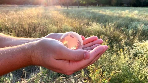 A man opens a glass globe in his palms and examines it Stock Footage 113968905