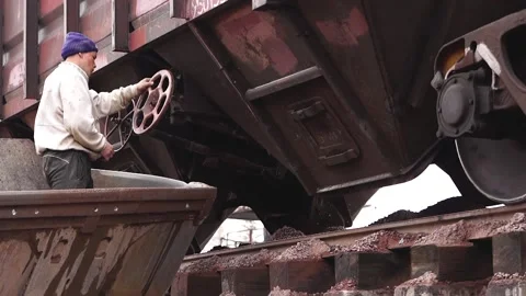 A man opens a hatch (door) to unload rubble from the train. Stock Footage 196087490