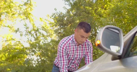 The man opens the hood of broken car with the emergency lights on, and opens the Stock Footage 134166252
