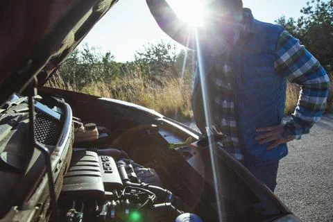 Man opens the hood of the broken down car on the side of the road. Roadside a Stock Photos