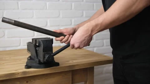 A man opens an iron pipe in a black vise with a screw handle and a cast-iron fra Stock Footage 146951851