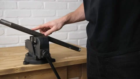 A man opens an iron pipe in a black vise with a screw handle and a cast-iron fra Stock Footage 146952369