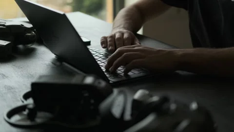 Man opens the laptop for editing. Silhouette. Filmmaker Edits. Drones next to it Stock Footage 243425335