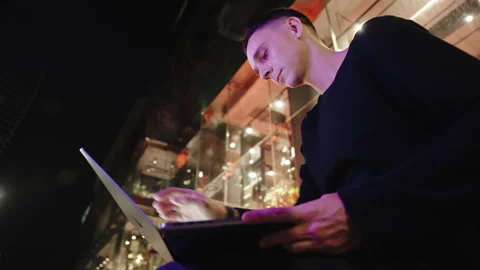 A man opens laptop in stylish jacket in the city at night Stock Footage 253223337