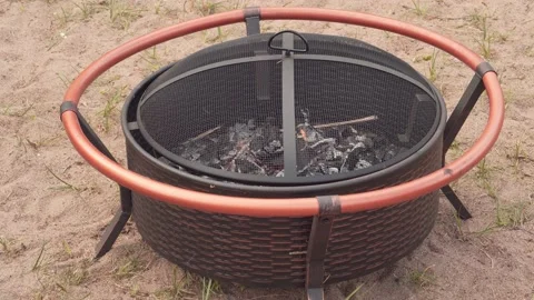 A man opens the lid of a fire pit with burning wood. Stock Footage 157288069