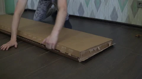 A man opens a new box with accessories for assembling the cabinet Stock Footage 143588531