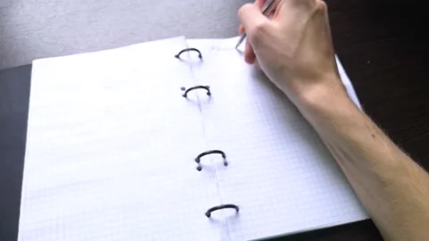 The man opens a notebook and begins to write down his ideas in it with a pen Stock Footage 160555725
